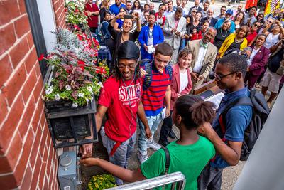 Students flip the switch to turn on rooftop solar installed on a rowhouse as part of the Solarize Philly program in 2018.