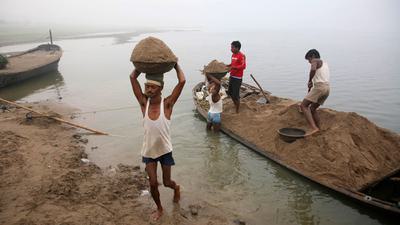 Laborers transport sand from the Yamuna River in India, where a construction boom has led to indiscriminate mining of river sand.