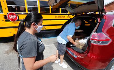 A woman picks up school-provided lunches at an apartment complex in Dallas, Texas.