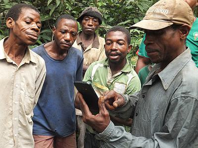 Baka community members learning how to use an app to report illegal poaching activity.