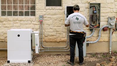 A technician installs a Base Power home battery system that will sell electricity to the power grid in Texas.