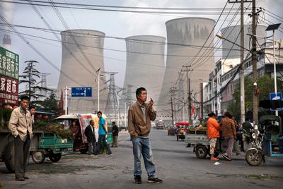 A coal plant looms over a street market in Huainan, China.