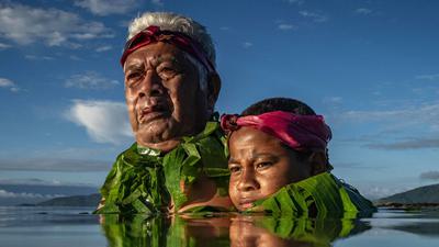 On Fiji's Kioa Island, Lotomau Fiafia and his grandson John stand where the shoreline used to be when Lotomau was young. As seas rise, the shoreline is retreating.