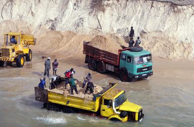 Trucks load illegally mined sea sand along beaches north of Dakar to supply Senegal's construction industry.