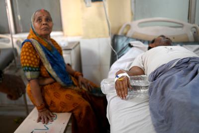 A woman keeps vigil on a man who suffered heatstroke during a 2024 heat wave in Varanasi, India.
