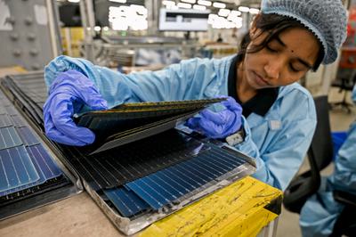 A worker inspects photovoltaic cells at a solar factory in Mundra, India.