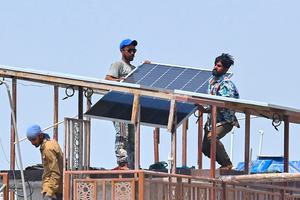 Technicians install rooftop solar panels in Karachi, Pakistan.