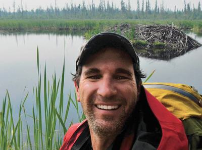Rob Mark at the dam, with the beaver lodge behind him.