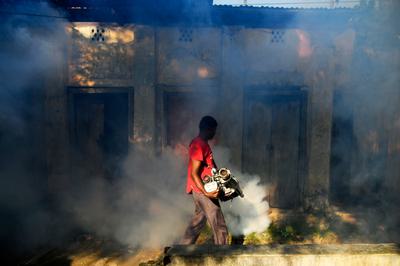A worker sprays insecticide in a crowded neighborhood in Dhaka to protect against dengue fever, July 18, 2023.