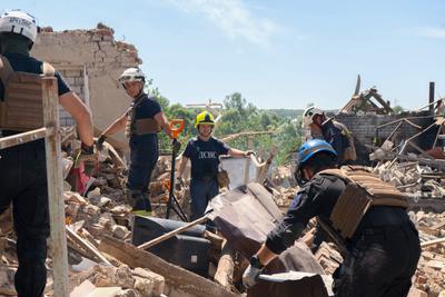 Workers clear rubble at a house hit by Russian shelling in Ruska Lozova.