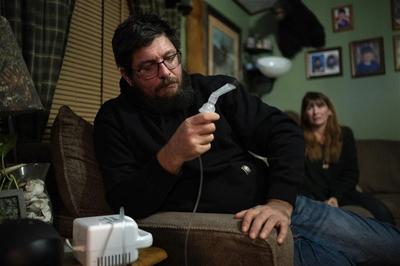 Justin Smarsh using a nebulizer at his home in Cherry Tree, Pennsylvania, with his wife Alicia in the background.