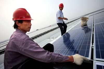 Workers install solar panels on the roof of the Hongqiao Passenger Rail Terminal in Shanghai, China.
