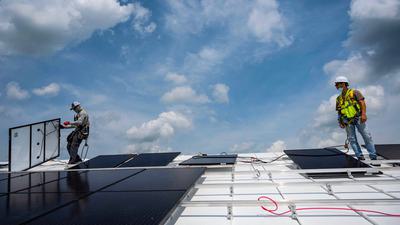 Workers install solar panels on Peace Lutheran Church in Alexandria, Virginia.